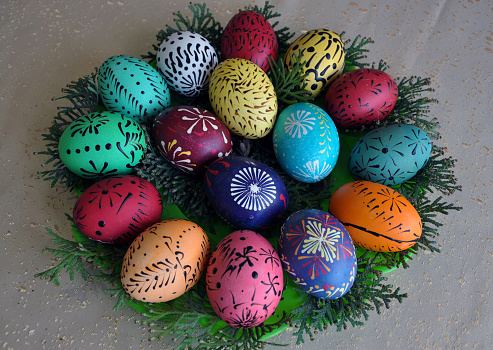 Easter eggs on turf grass and blue wooden wall with spring vivid flowers