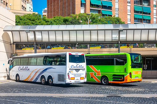 Barcelona, Spain - September 10, 2022: Close up of two buses parked near each other in a parking lot. The area has a parking shade canopy, and one of the buses has the word \
