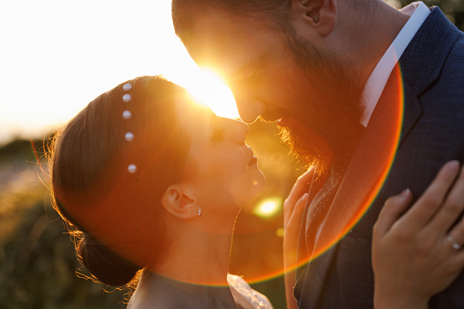 Close-up photo of newlywed young couple sharing love in nature at sunset