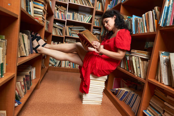 istock Woman in red dress in a library 1424846077