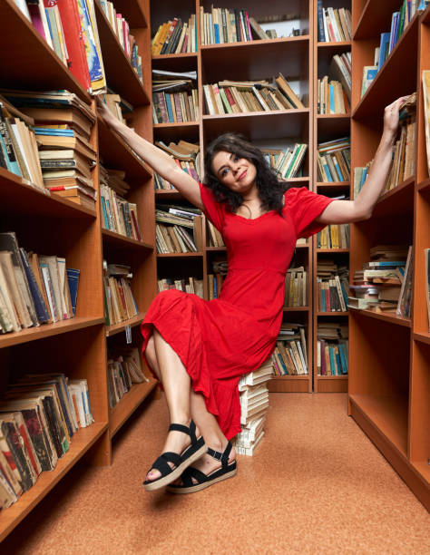istock Woman in red dress in a library 1424846108