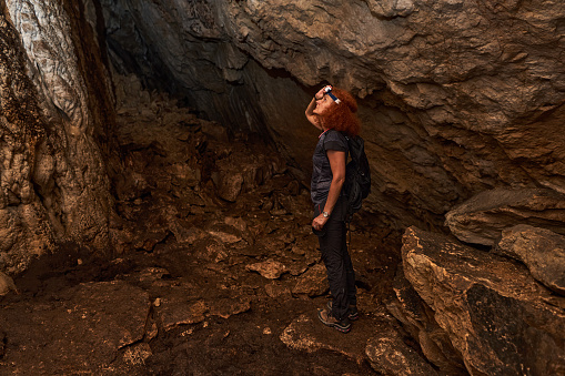 Woman with headtorch exploring a very old cave with beautiful speleothemes