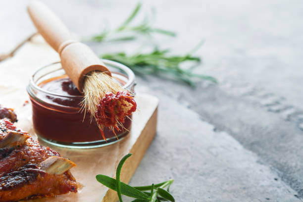 salsa barbacoa picante y picante en tazón de jarra con pincel de bastidor sobre fondo gris piedra vieja. composición plana laica. concepto de comida americana. vista superior. espacio para texto - marinated fotografías e imágenes de stock