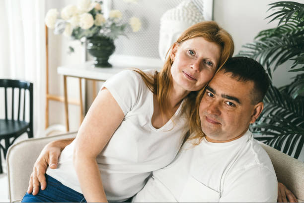 istock Middle-aged married couple hugging on the couch. 1424849969