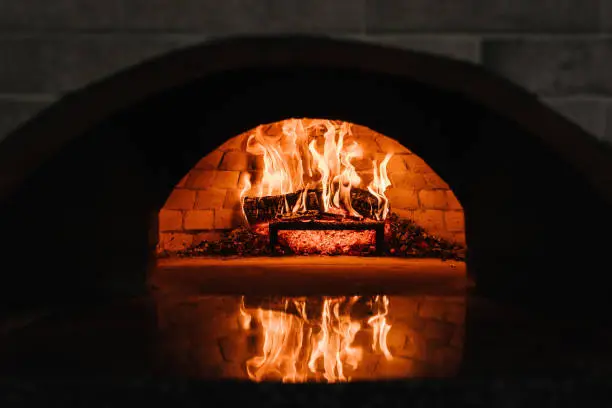 Photo of Firewood burning in the oven. Wood-fired oven. Image of a brick pizza oven with fire. A traditional oven for cooking and baking pizza.