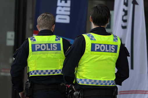 Swedish police in uniforms entering the ice and handball venue, Malmö Arena on a sunny day in Malmö, Sweden