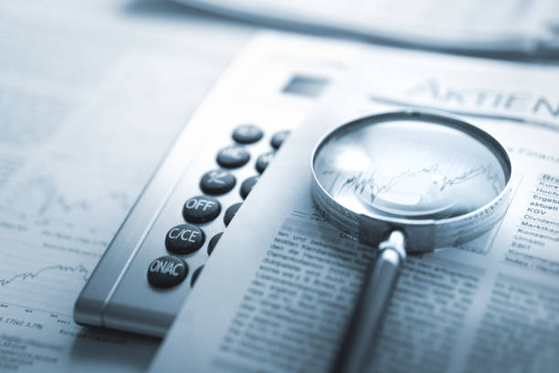 istock Magnifying glass, calculator and charts on newspaper 1424858453