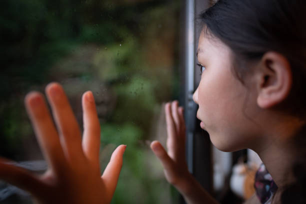 Cute little girl looks out the red window and making a face