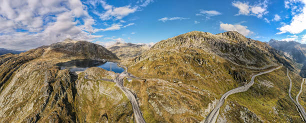 aerial view overlooking the Grimsel Pass summit in the swiss alps View of the top of the pass, the Totensee reservoir, the road and the partly cloudy sky. The famous swiss mountain pass roads Grimselpass, near the Furkapass, canton of Valais on the border with canton of Bern, switzerland grimsel pass photos stock pictures, royalty-free photos & images