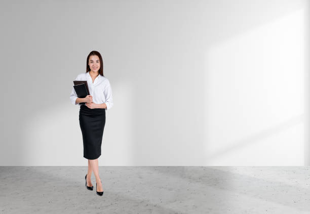 istock Young businesswoman with notebook on grey concrete floor, white empty background 1424871493