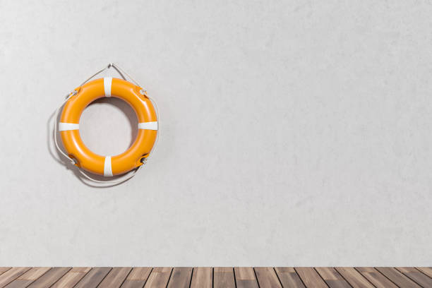 istock Lifebuoy on grey concrete wall, hardwood floor. Copy space 1424871518