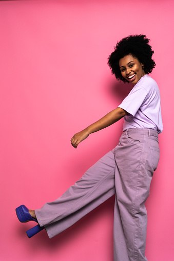 Portrait of a young woman showing shoe on a pink background
