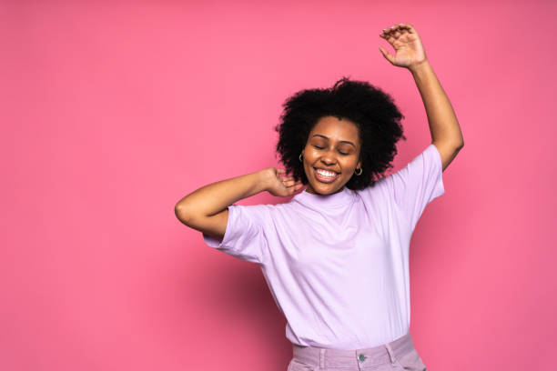 istock Happy young woman dancing on pink background 1424871649