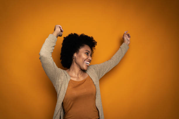 istock Happy young woman dancing on orange background 1424871772