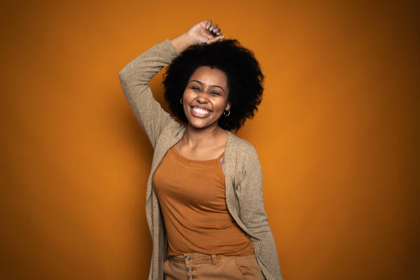 istock Happy young woman dancing on orange background 1424871818