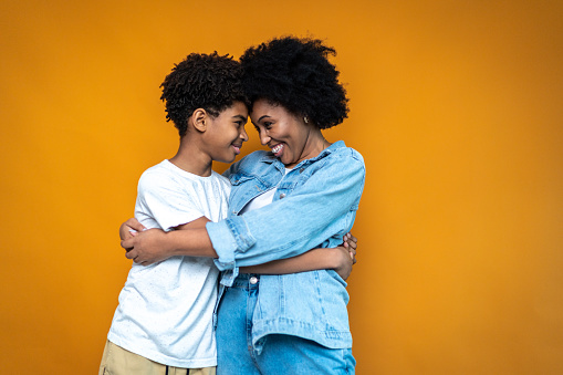 Siblings embracing on orange background