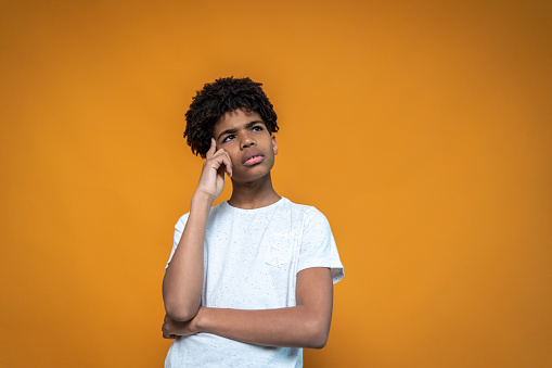 Thoughtful boy on an orange background