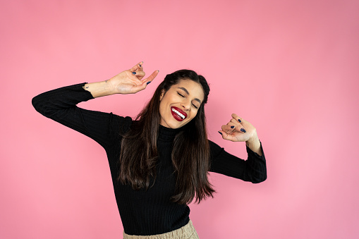 Portrait of a young woman dancing on a pink background