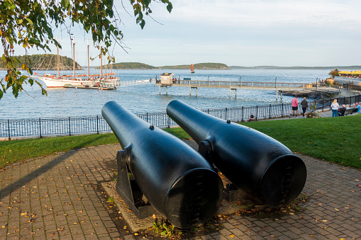 Bar Harbor, USA - Octobe 12, 2021. Cannons facing Frenchman Bay with people walking on promenade, Bar Harbor, Maine, USA