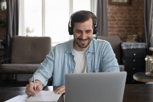 istock Happy millennial laptop user man wearing wireless headset 1424880435