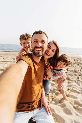 Photo of a smiling family taking a selfie at the beach