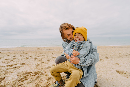 Photo of a little boy and his  mom spending an autumn day at the beach