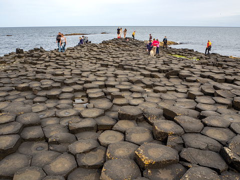County Antrim, Northern Ireland, UK - July 27, 2019: Visitors on Giants Causeway, unique hexagonal geological formation of volcanic basalt rocks. Famous tourist attraction of Northern Ireland