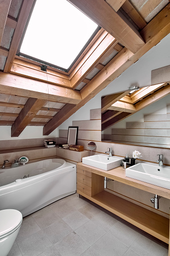 interior view of a modern bathroom in the attic room in the foreground of the countertop washbasin