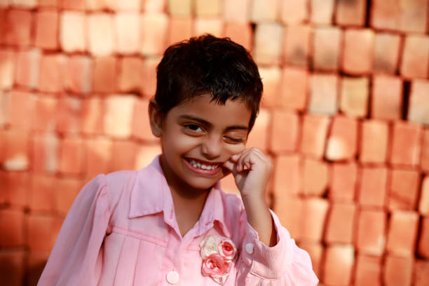 Cheerful cute child of Indian ethnicity portrait on brick wall.
