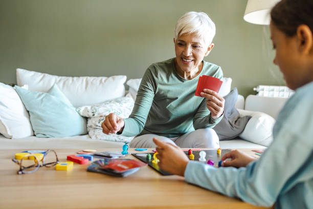 Grandmother and grandmother playing board games at home Beautiful grandmother playing board games with a child at home. They are cheerful and playful family playing card game stock pictures, royalty-free photos & images