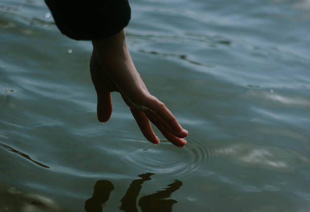 istock Hand reaching towards blue waves of water 1424897517