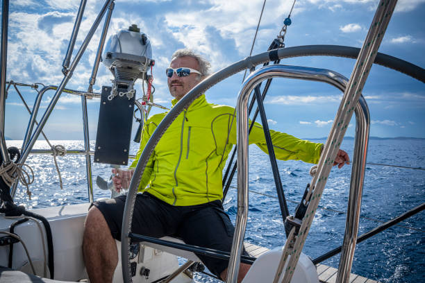 the man holding a beer glass is driving a sailboat and enjoying it. - yacht nautical vessel autopilot sailing imagens e fotografias de stock