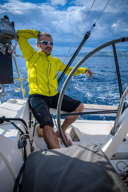 the man drives a sailboat on an autopilot and enjoys it. - yacht nautical vessel autopilot sailing imagens e fotografias de stock