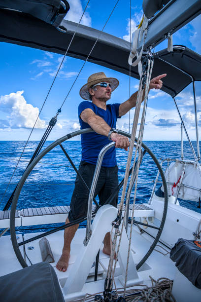 a man wearing a straw hat  is driving a sailboat and enjoying it. - yacht nautical vessel autopilot sailing imagens e fotografias de stock