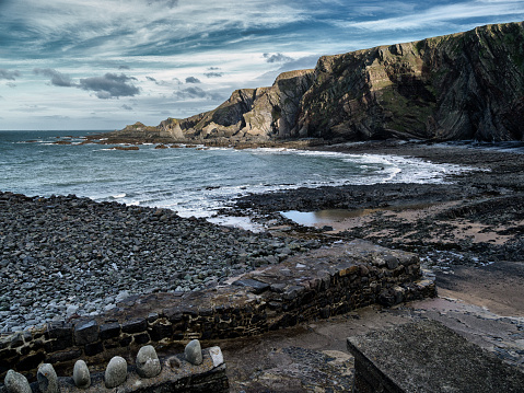 A cold winter’s day at Hartland Quay, Devon, where the calm sea hides the rocks that have wrecked many a ship in years gone by. The shadows hint that twilight approaches.
