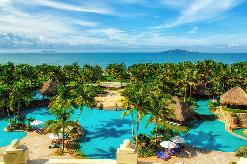 Beautiful view of the pool and stunning palm trees in Wuzhizhou Island. Tropical island for relax and water activities. Haitang Bay. Hainan Province.