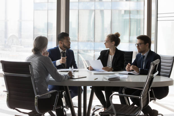 Busy millennial professional group reviewing startup marketing reports stock photo