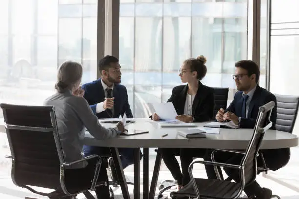 Photo of Busy millennial professional group reviewing startup marketing reports