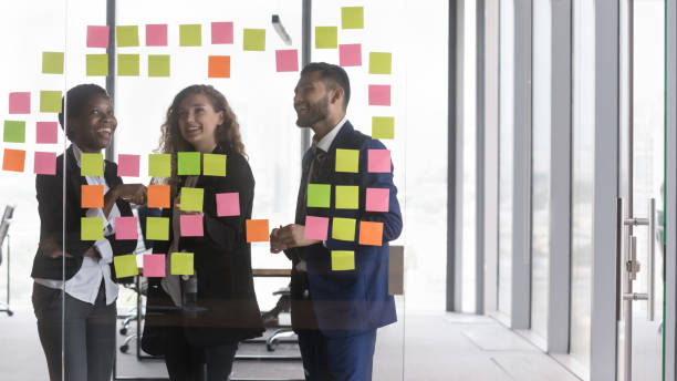 istock Happy diverse millennial business team meeting at board with notes 1424912458