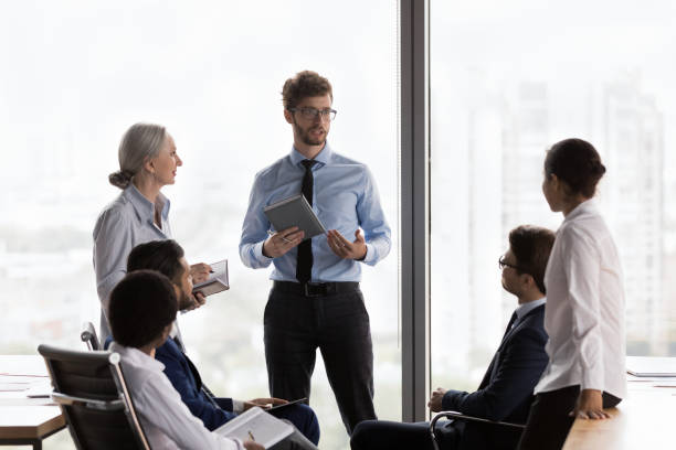 istock Confident young CEO man talking to team, speaking, instructing employees 1424912560
