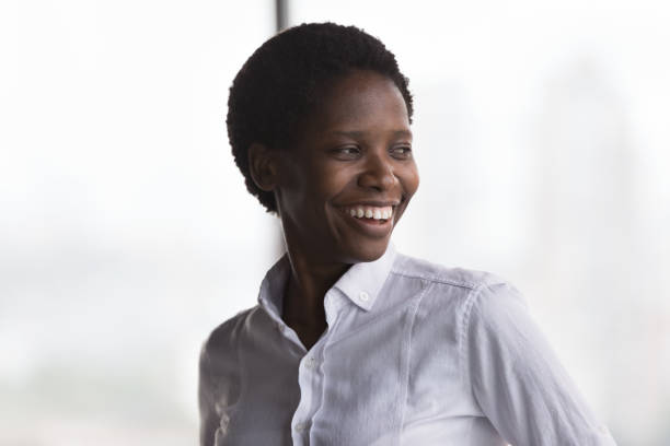 Happy cheerful African American business leader woman looking away
