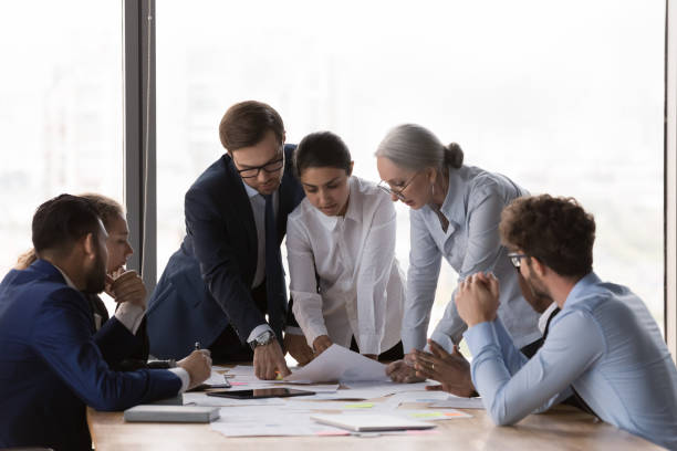 istock Serious diverse business group discussing project reports at meeting table 1424912675