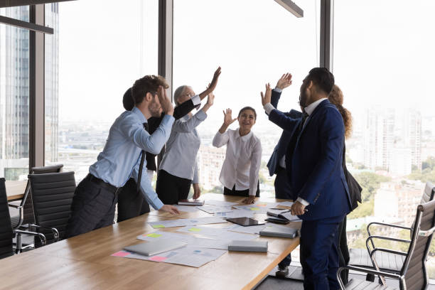 istock Excited business colleagues giving group high five over meeting table 1424912844