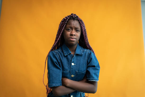 портрет разгневанной девушки на оранжевом фоне - teenage girls studio shot looking at camera waist up стоковые фото и изображения