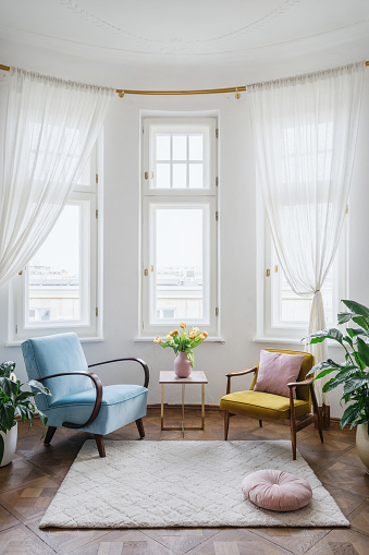 Concept of simple living. Blue and yellow armchairs standing near coffee table with flowers. Vintage style in interior. Comfortable apartment with old fashionable furniture and retro design in room