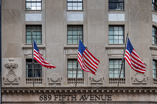 5th Avenue, Manhattan, New York, NY, USA - July 17th 2022: Three American flags on poles on a façade at 689 Fifth Avenue