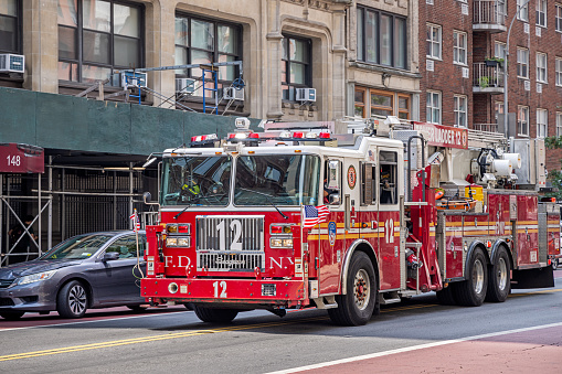 Manhattan, New York, NY, USA - July 16th 2022:  Fire truck in the narrow West 23rd Street in front of a scaffolding