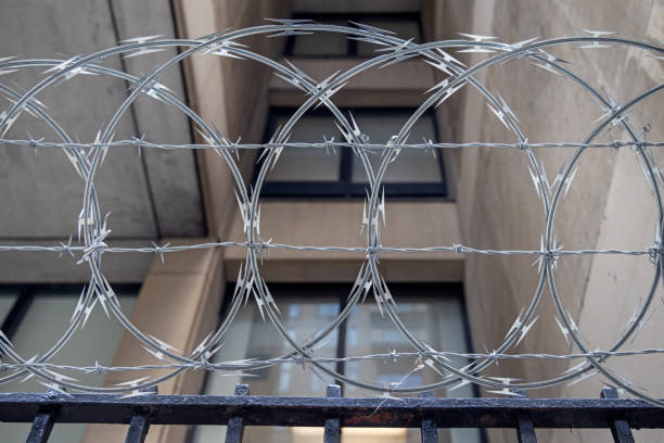 barbed wire in front of a residential building - razor wire imagens e fotografias de stock