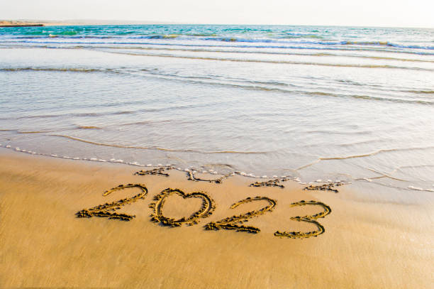 istock happy new year 2023 on beach 1424921196