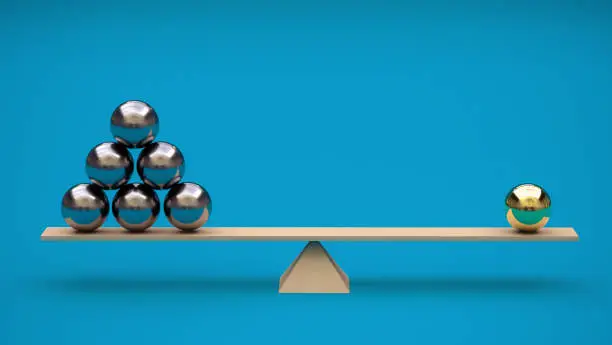 Photo of One gilded ball is balanced on a swing by several metal balls. 3D rendering. Minimalism. Abstraction. Balance concept. Leadership. Not like everyone else
